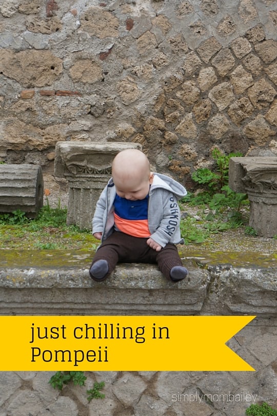 baby boy sitting on a wall in pompeii italy