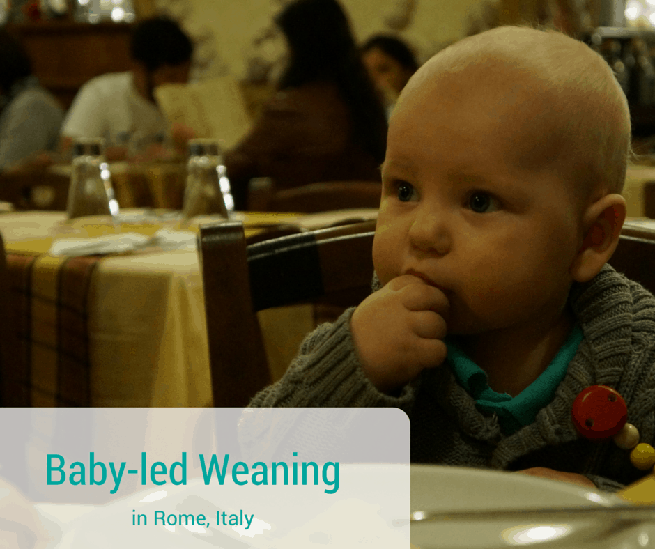 baby eating food in Rome in a high chair at a restaurant.